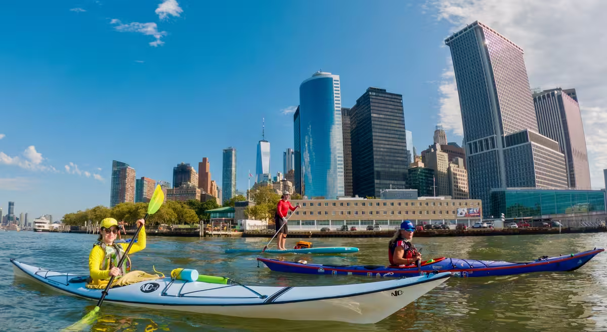 Two kayaks and a paddleboard on the confluence of the Upper NY Bay and the southern end of the Hudson River at the NYC Battery.