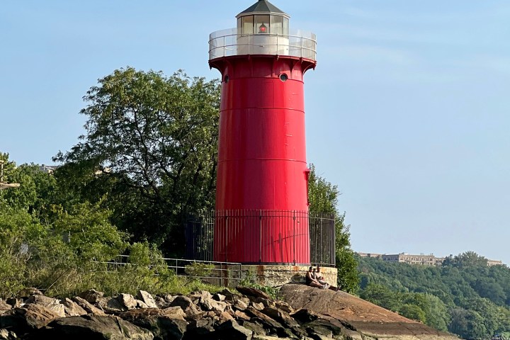 a small clock tower in the middle of a body of water with Kenosha Light in the background
