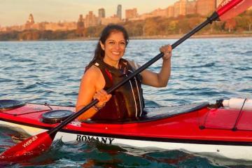 a woman in a red Romany sea kayak on the Hudson River in NYC