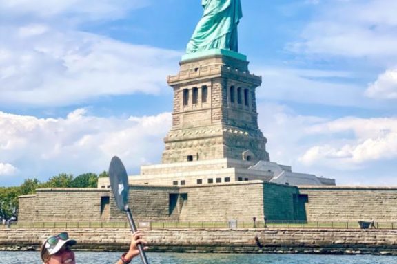 a woman riding a kayak at the Statue of Liberty