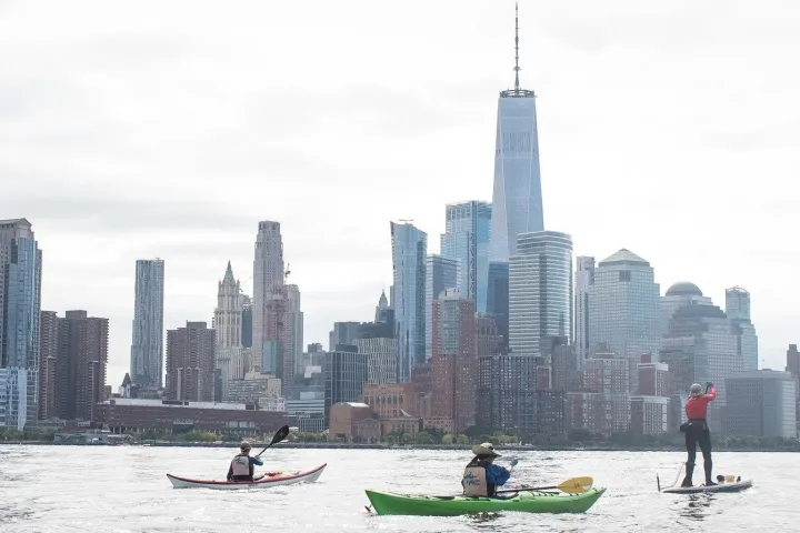 a group of people in a body of water with buildings in the background