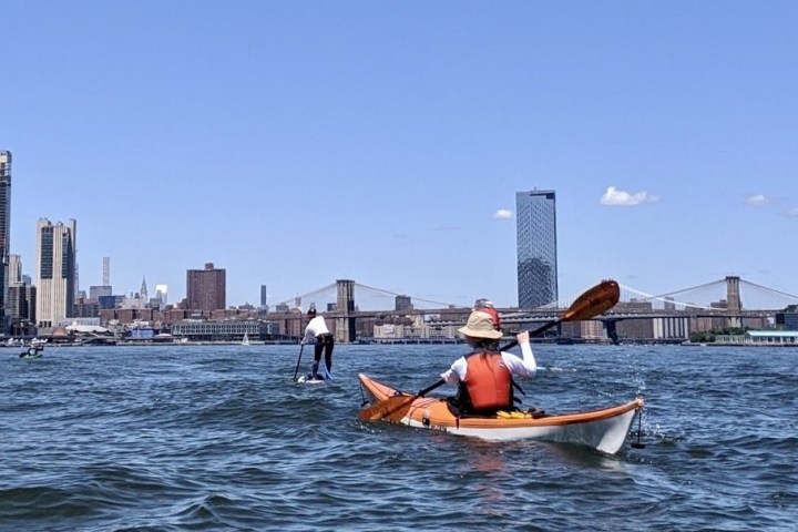 a small boat in a body of water with a city in the background