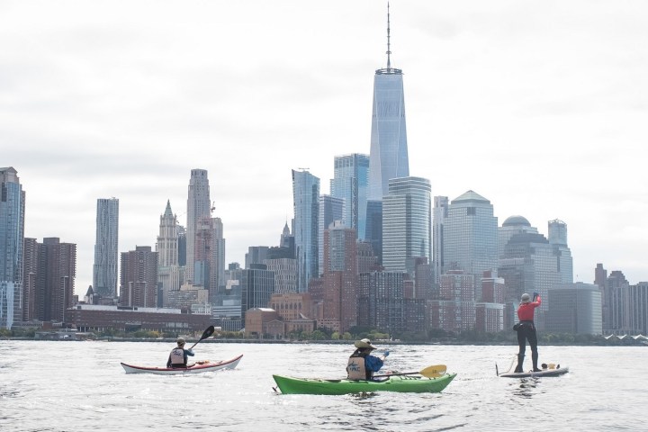 a group of people riding kayaks and SUPs on the Hudson River
