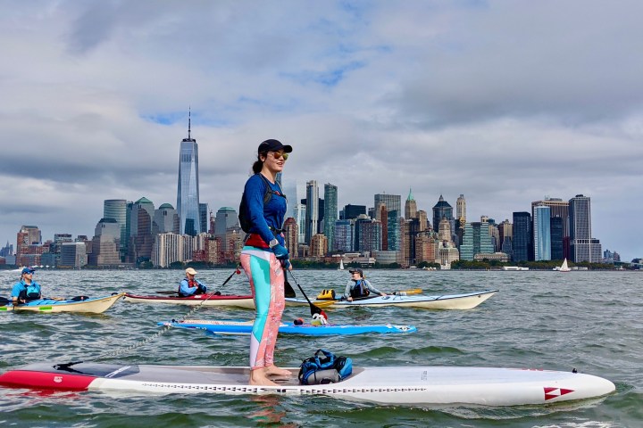 a group of people riding kayaks and stand up paddle boards on the Hudson River in NYC