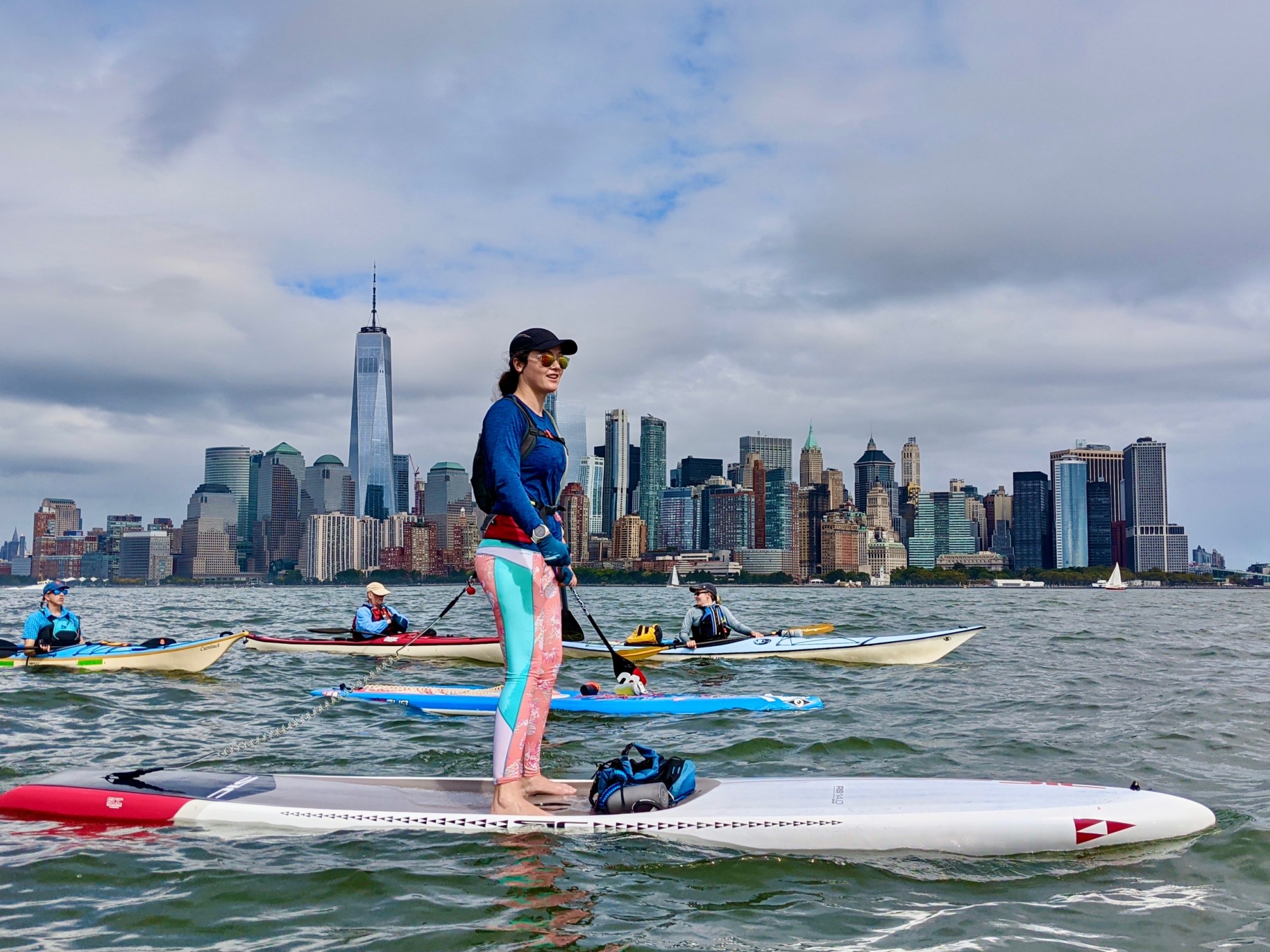 Surf City Trip a group of people riding kayaks and stand up paddle boards on the Hudson River in NYC