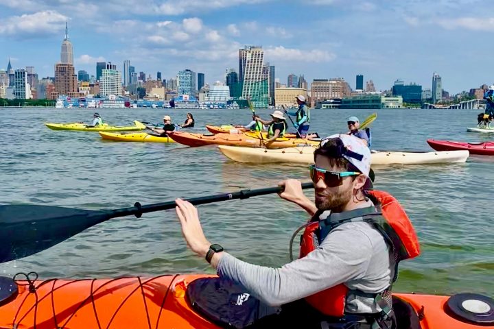 a man in an orange kayak on the water near Manhattan