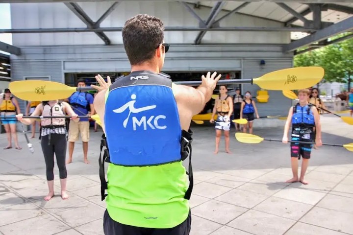 A Manhattan Kayak Co instructor standing on Pier 84 showing a group of people how to kayak, helping them to build basic kayak stroke technique before their first launch onto the Hudson.
