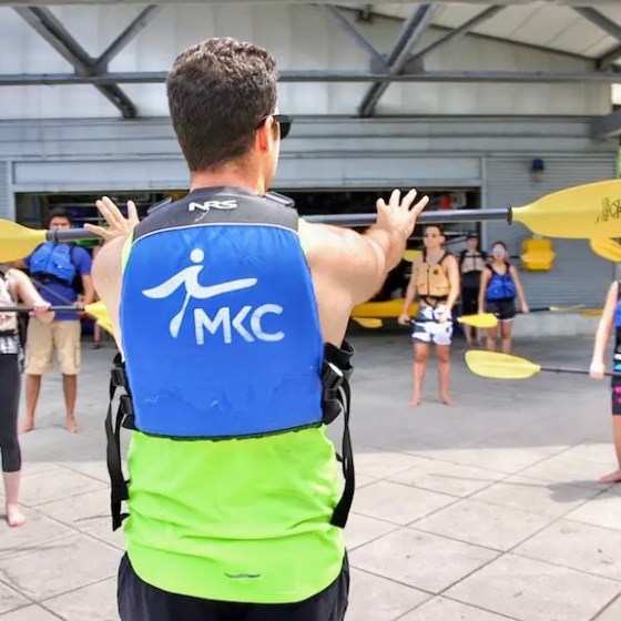 A Manhattan Kayak Co instructor standing on Pier 84 showing a group of people how to kayak, helping them to build basic kayak stroke technique before their first launch onto the Hudson.