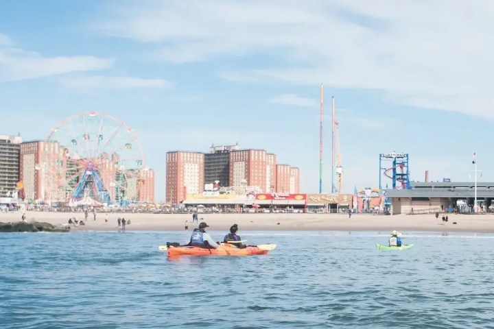 A couple in a tandem sea kayak paddling toward Luna Park in Coney Island.