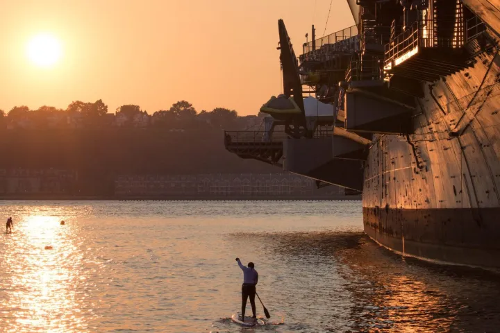a paddle boarder at sunset by the Intrepid