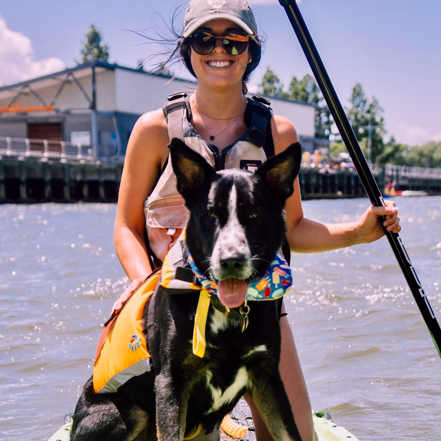 A woman and her dog sharing a moment on a paddleboard at the Pier 84 boathouse. Dog-friendly paddleboarding in NYC at Manhattan Kayak, showing a calm and easy launch from the Hudson River Park pier.