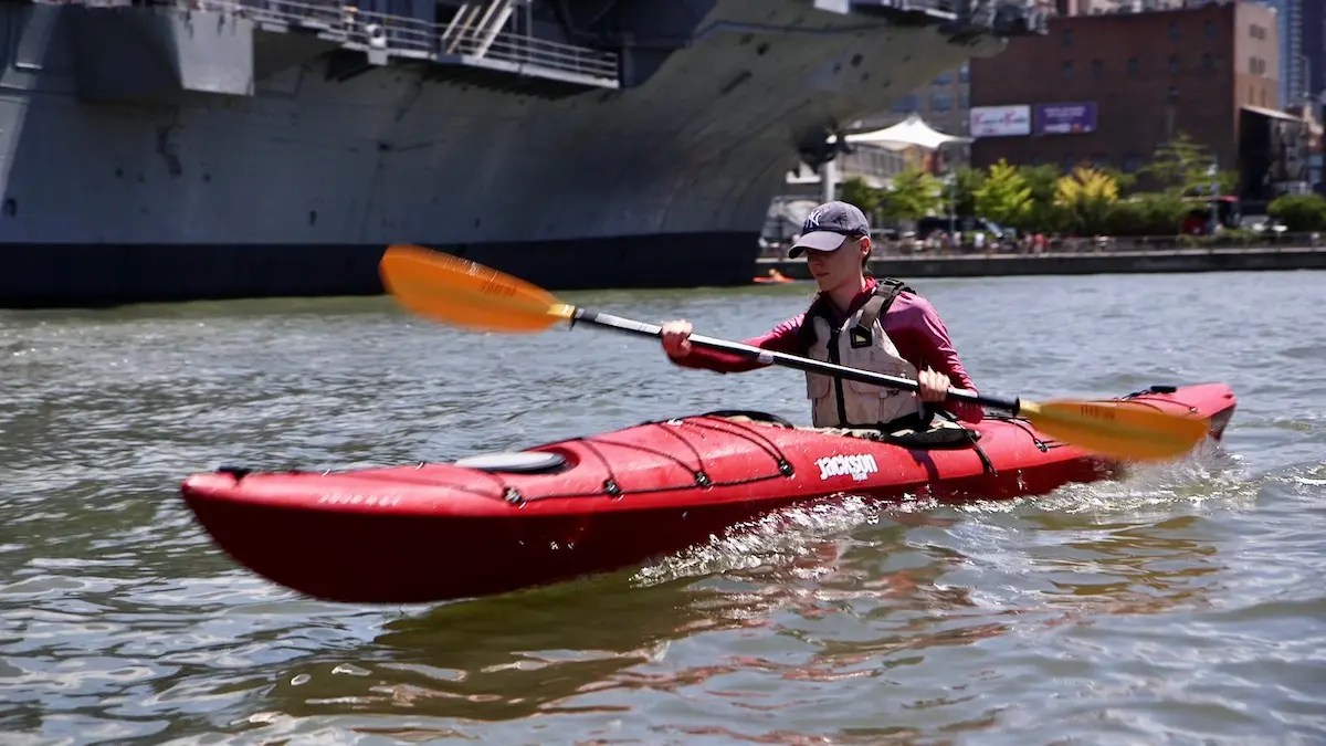 A focused student trading the treadmill for the Hudson River, generating power and a clean wake during a quiet weekend Kayak Basics class.