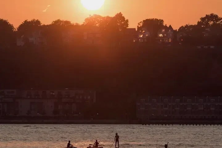 Kayakers and paddleboarders on the golden water of the Hudson River at sunset in NYC. Photo by maximusupinnyc