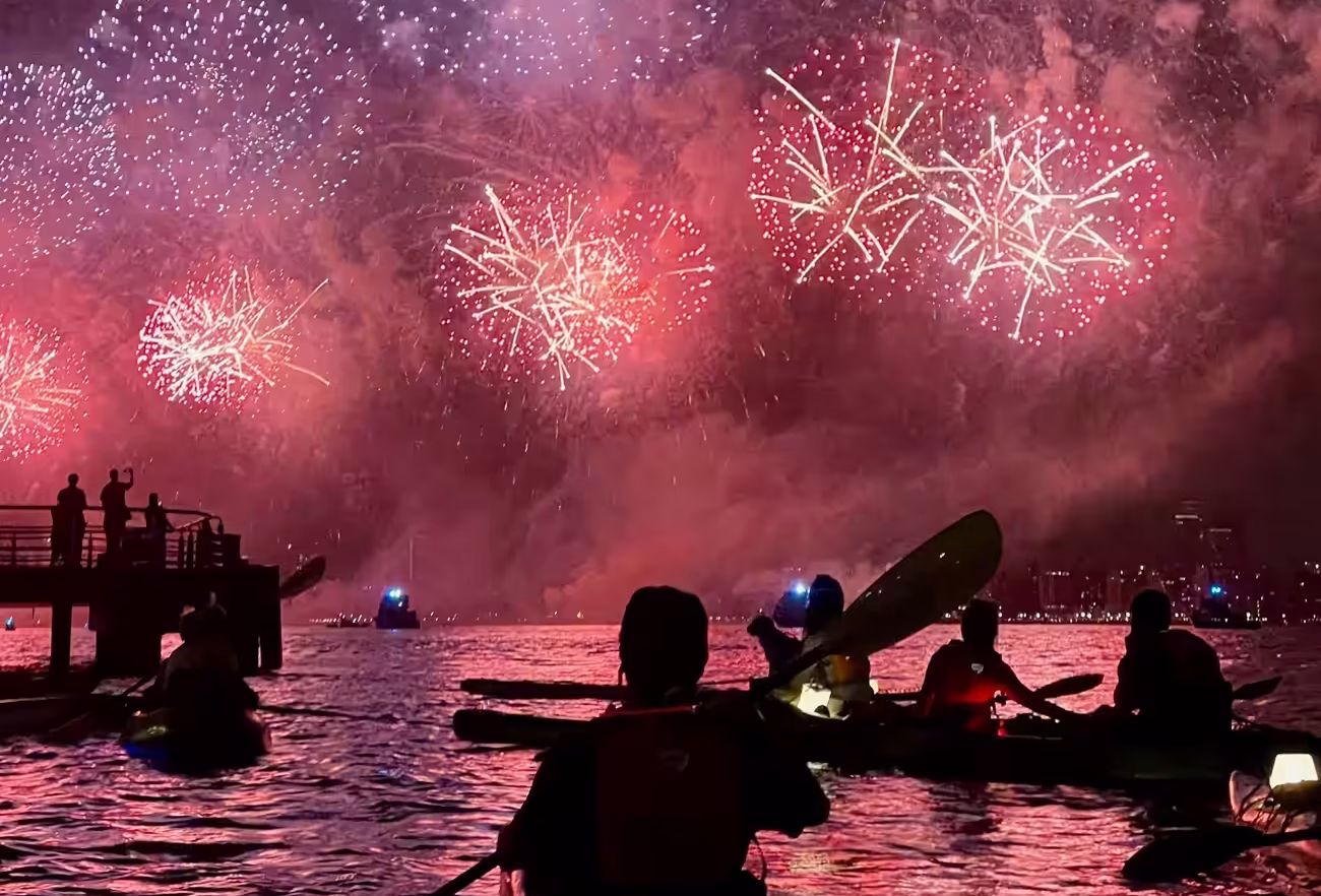 Kayakers watching the red bursts of Macy's Fourth of July fireworks on the Hudson River.