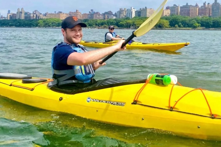 Two students in yellow Wilderness Systems sea kayaks practice navigating the open Hudson River during a Kayak Basics 3 class, with the Upper West Side skyline in the background.