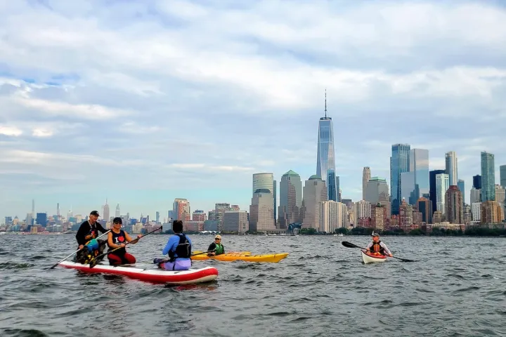a group of people on kayaks and SUPs in the New York Harbor