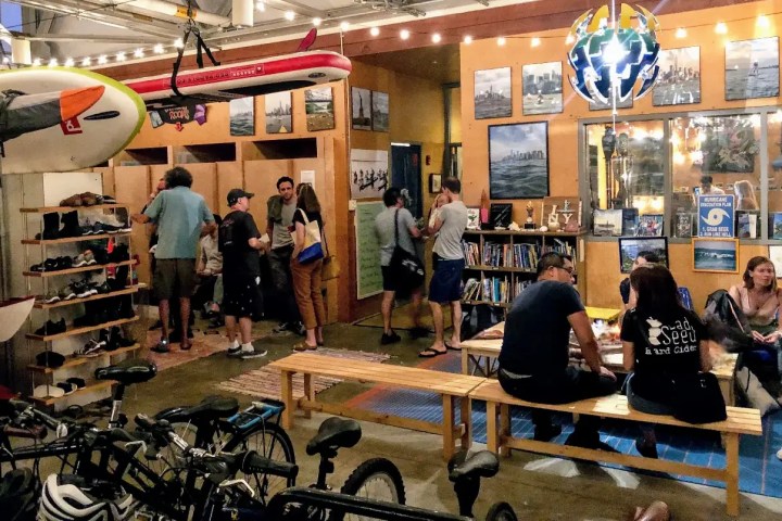 A group of professionals relaxing in a modern NYC boathouse with wooden lockers and an adventure library.