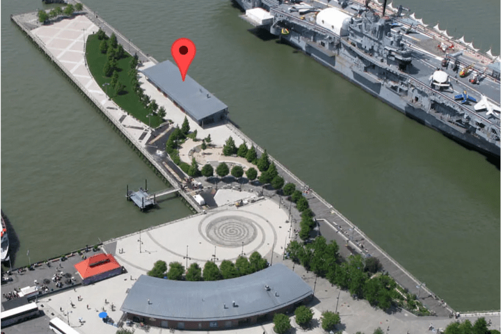 Pier 84 Boathouse as seen from above with curved green landscaping spanning the length of the pier and a 4.5 acre protected cove along the USS Intrepid Aircraft Carrier.