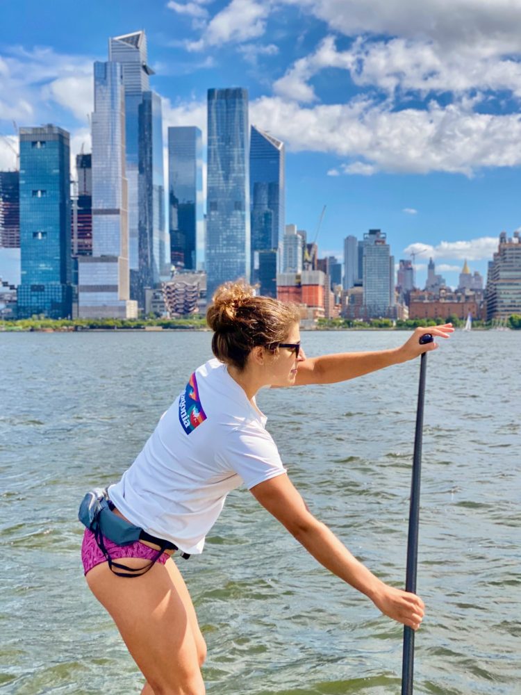 a person standing in a body of water with a city in the background