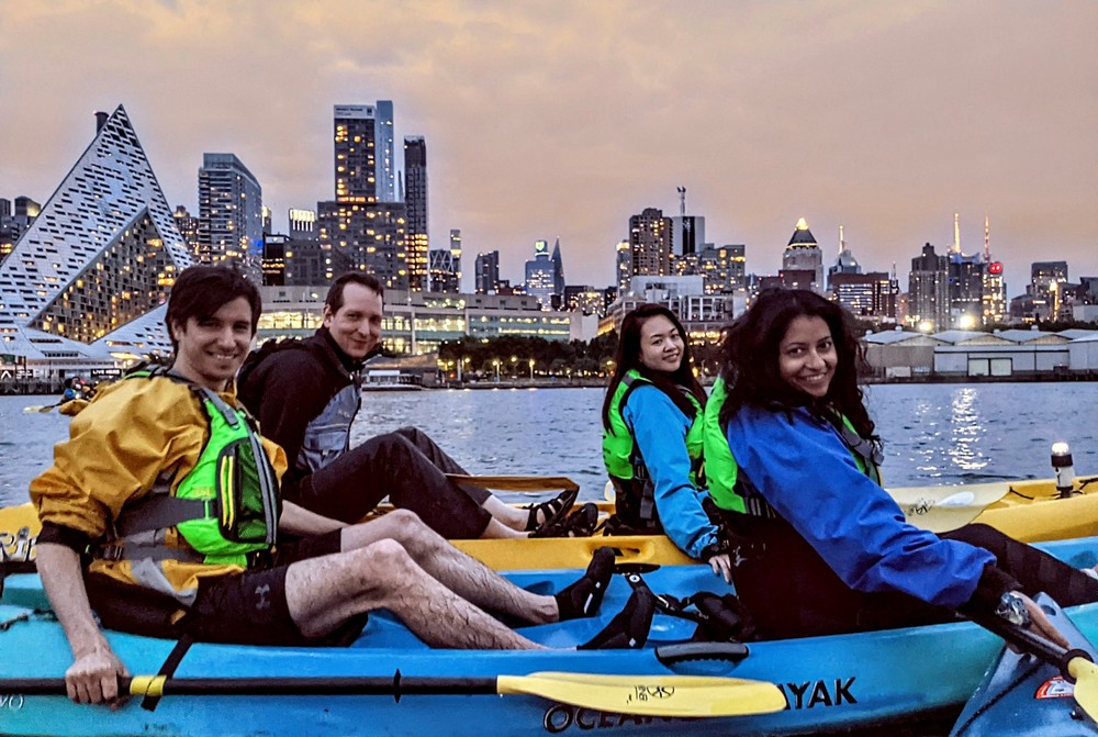 A couple enjoying a serene, private kayak tour in stable tandem boats, experiencing the quiet beauty of the NYC waterfront and city lights away from the crowds.
