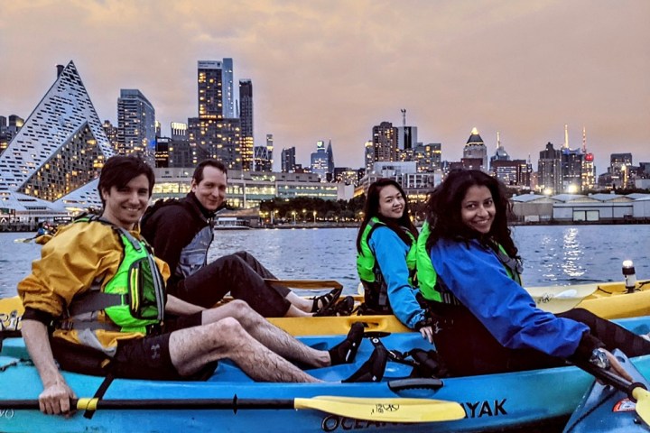 A couple enjoying a serene, private kayak tour in stable tandem boats, experiencing the quiet beauty of the NYC waterfront and city lights away from the crowds.