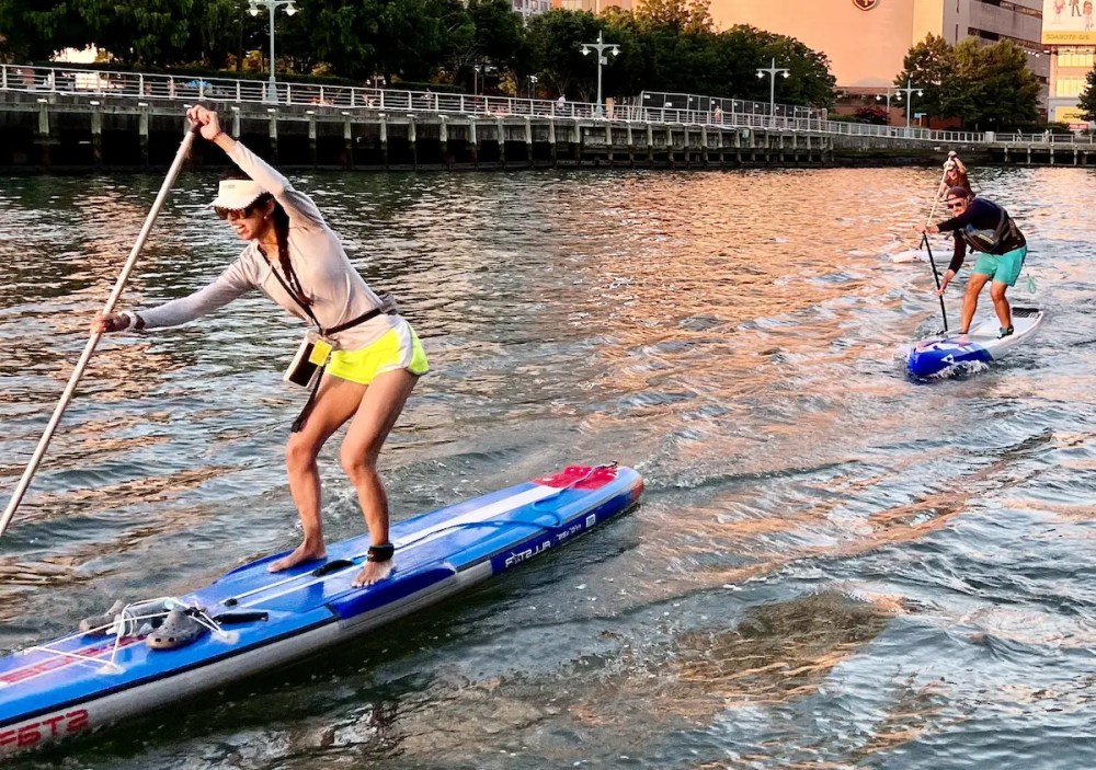 An MKC expert leading a SUP Basics class on the Hudson River, demonstrating the hinge technique to maintain balance and core power.