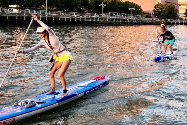An MKC expert leading a SUP Basics class on the Hudson River, demonstrating the hinge technique to maintain balance and core power.