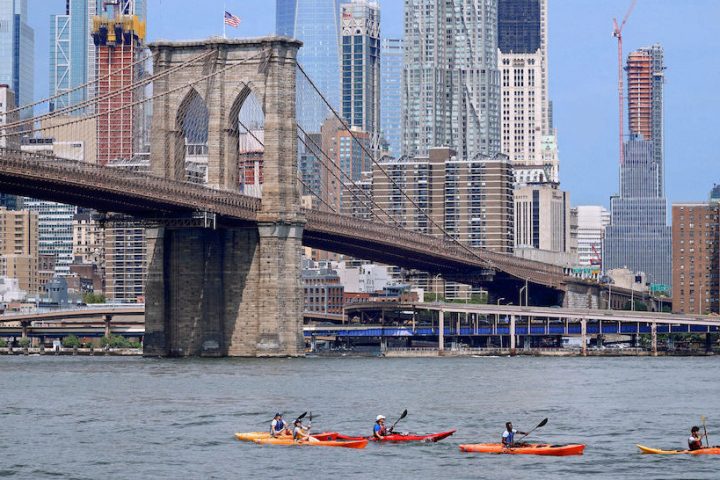 five kayakers on the East River near the Brooklyn Bridge
