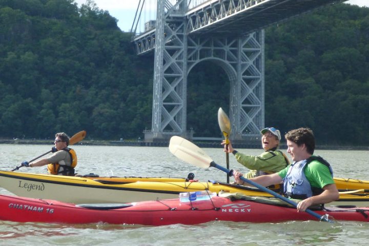 a woman and two men riding sea kayaks on the Hudson River under the George Washington Bridge
