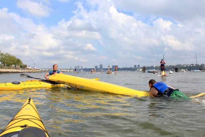 A Manhattan Kayak Co instructor teaching a student how to wet exit and re-enter a sea kayak on the Hudson River.