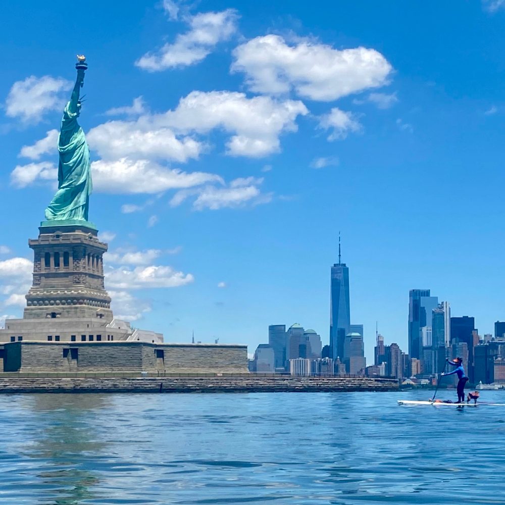 a paddle boarder at the statue of liberty