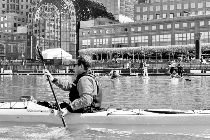 a man riding on the back of a boat in the rain