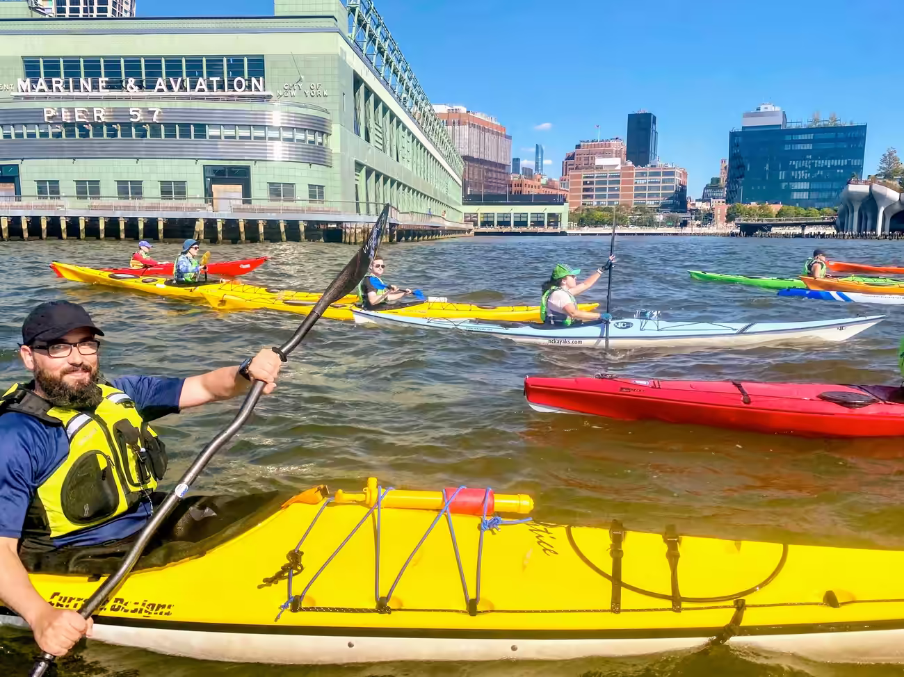 A group of sea kayakers riding in front of Pier 57 on the Hudson River in Manhattan.