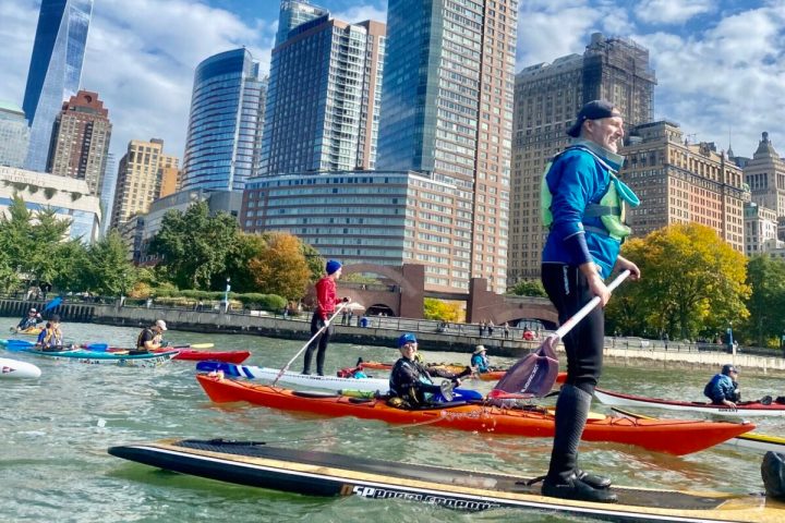 people riding kayaks and paddle boards at the NYC Battery