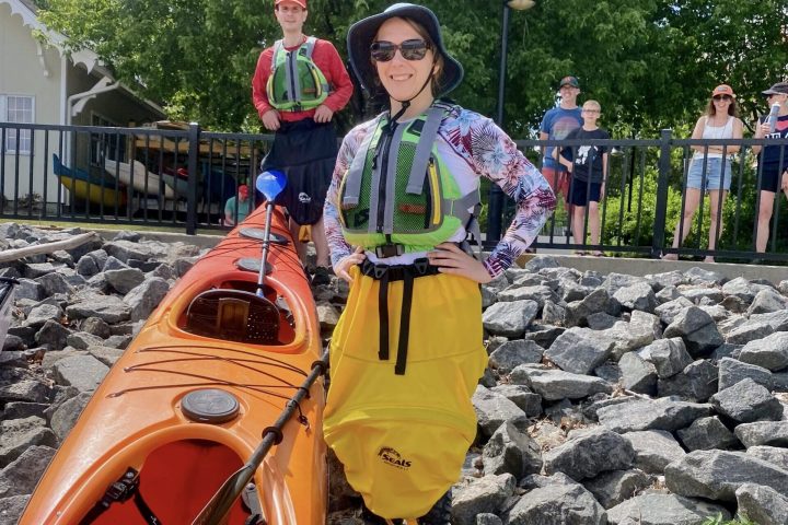 a man and woman standing next to a touring kayak