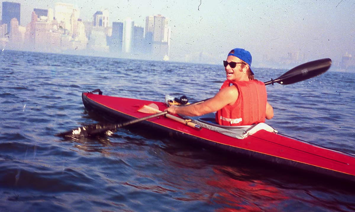 The beginning of a movement. David Lee Roth in a red Klepper sea kayak in the Upper New York Bay, looking back at the camera with his trademark grin. A hazy Downtown Manhattan skyline is on the horizon. David wears a backwards blue cap, sunglasses, and a bulky orange PFD. This rock star was Eric Stiller’s first paying client. David asked Eric take him on many unconventional explorations, e.g. from Gansevoort to Coney Island in the darkness of night. Also, David would urge Eric to pull up along shore so they could eat and drink even when there was no place to land. Many of Manhattan Kayak Co’s trip routes today were discovered through these two men’s adventures NYC together.