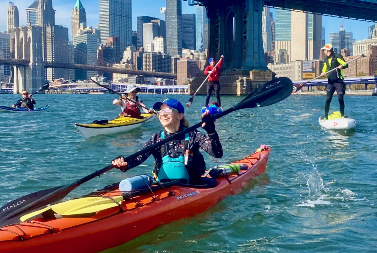 Circumnavigation-kayak-adventure-with-Stacey-Hull-at-Manhattan-Kayak-Co a group of people riding on the back of a boat in the water