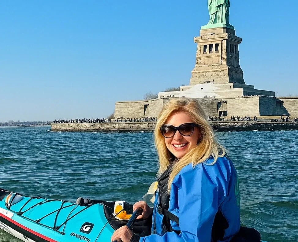 A woman kayaking in front of the Statue of Liberty with Manhattan Kayak Co.