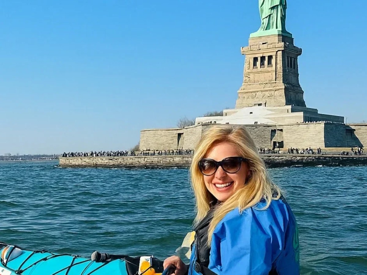 A woman kayaking in front of the Statue of Liberty with Manhattan Kayak Co.