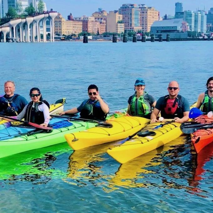 a group of kayakers and paddleboarders on the Hudson River in NYC