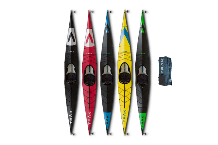 Five colorful TRAK kayaks in black, red, blue, yellow, and green with a TRAK gear bag.