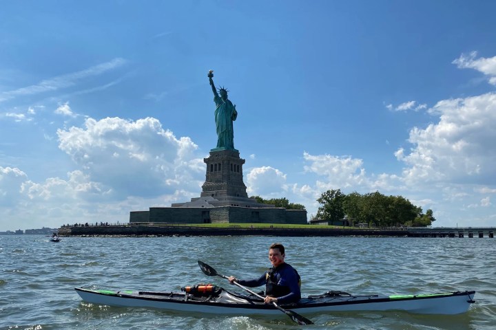 Man kayaking on a TRAK Kayak near the Statue of Liberty on a sunny day.