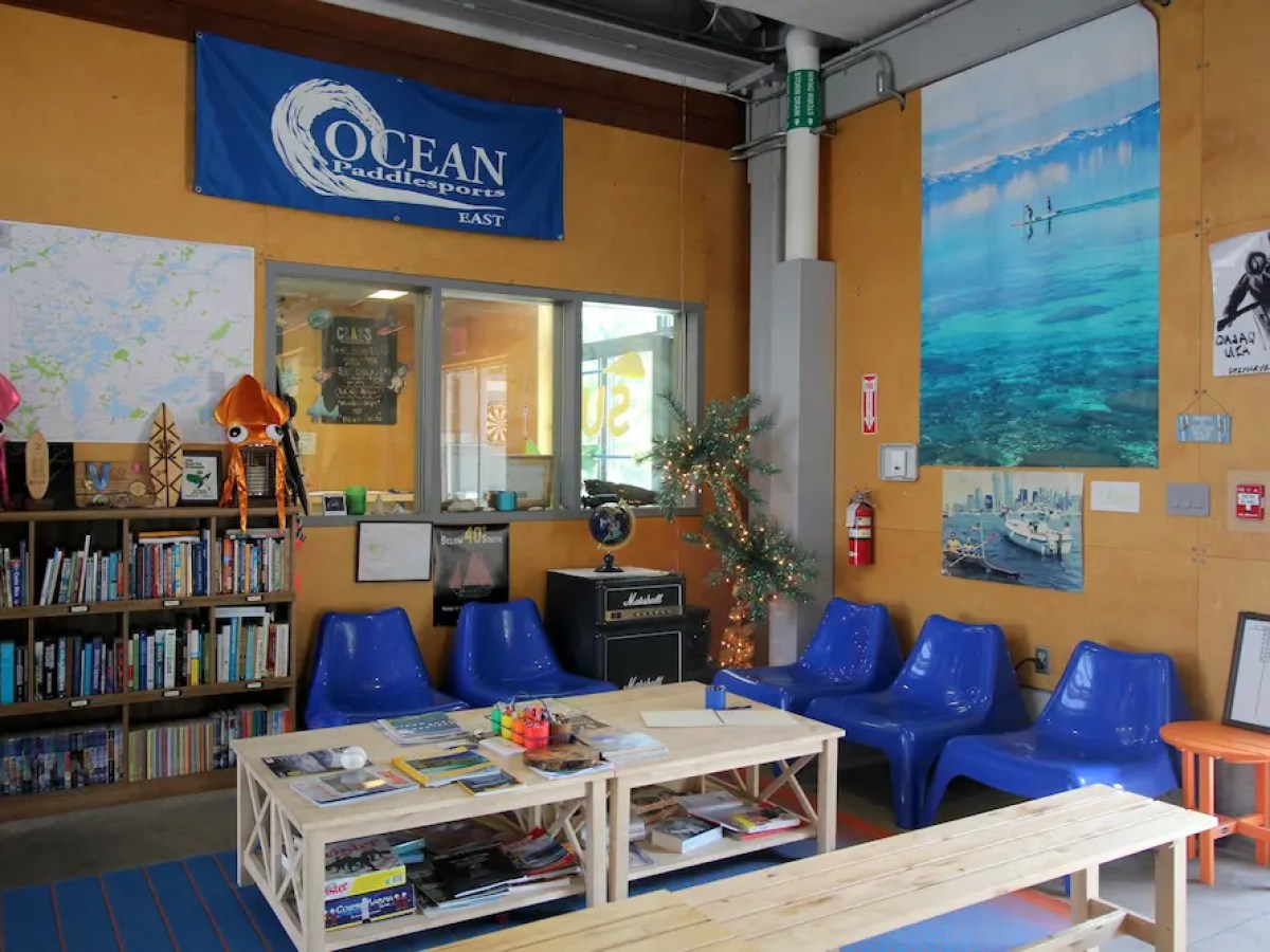 Cozy lounge with blue chairs, bookshelf, ocean-themed decorations, and a small table with magazines.