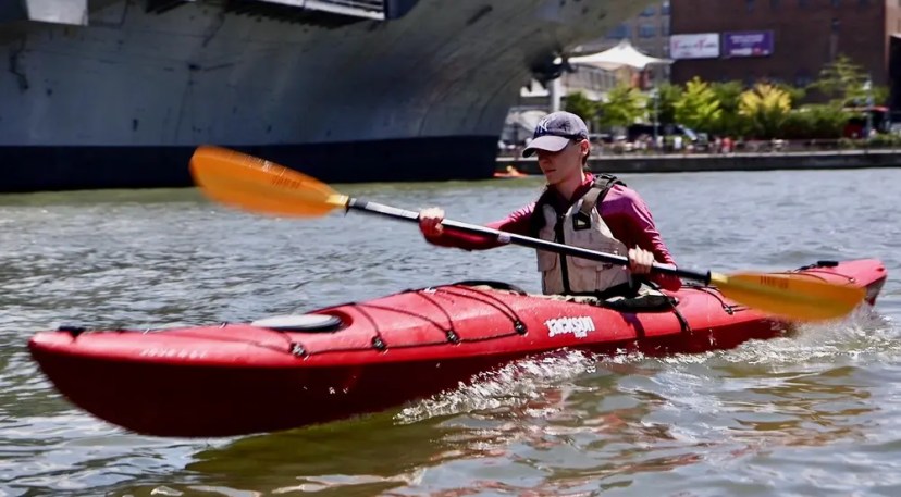 A focused student trading the gym for a sea kayak on the Hudson River, generating power and a clean wake during a weekend Kayak Basics class.