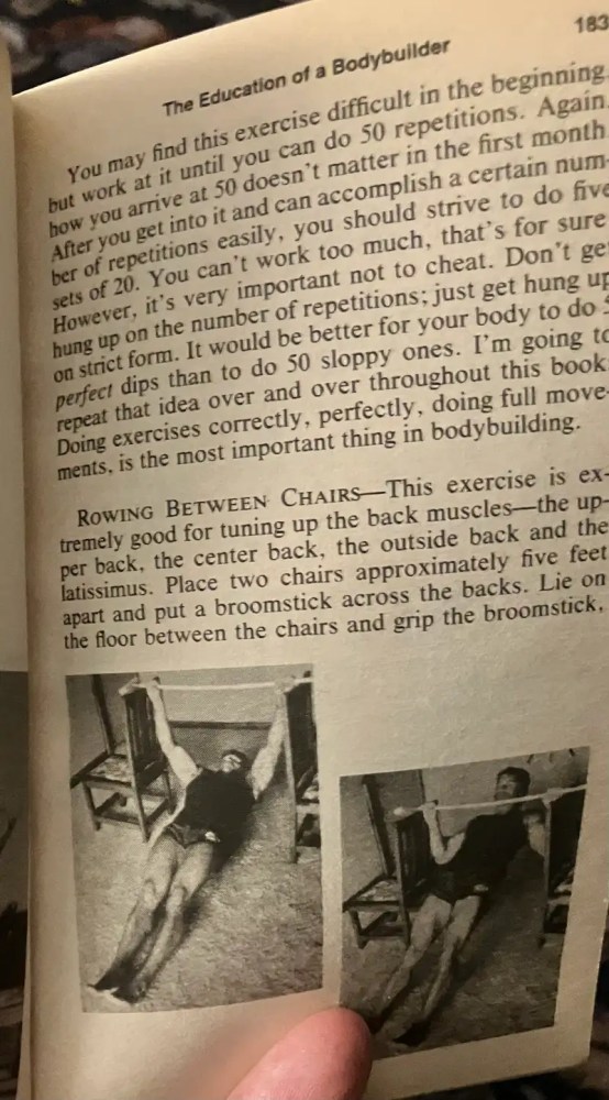 Open book showing an exercise description with a photo of a person lying between chairs.