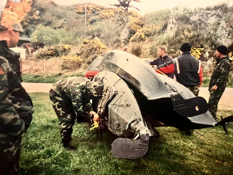 Group of people in military uniforms handle military equipment outdoors.