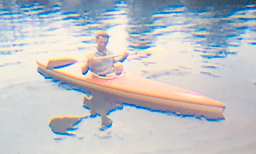 Person and child in a yellow kayak on calm water.