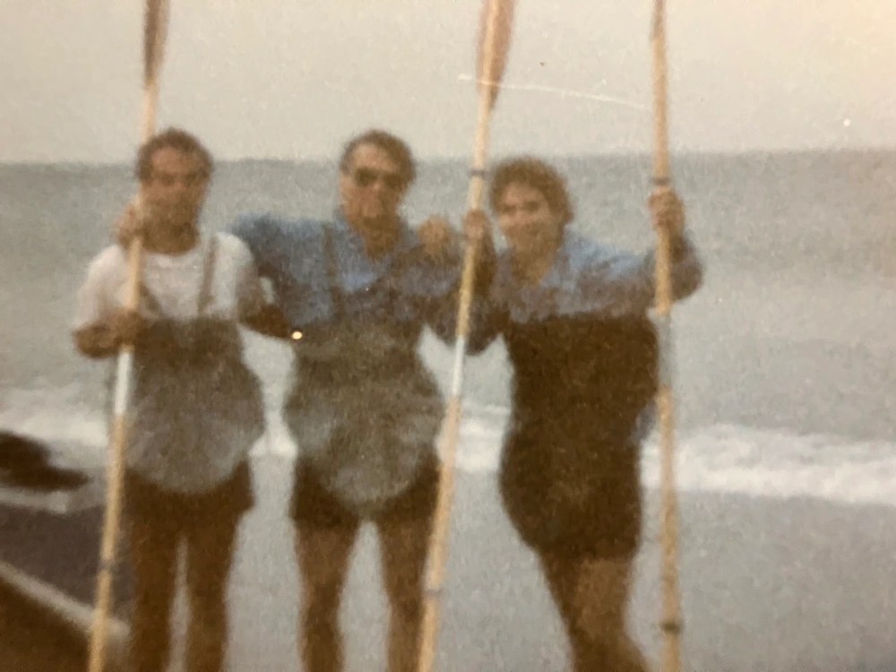 Three people with paddles on a beach, blurry photo.