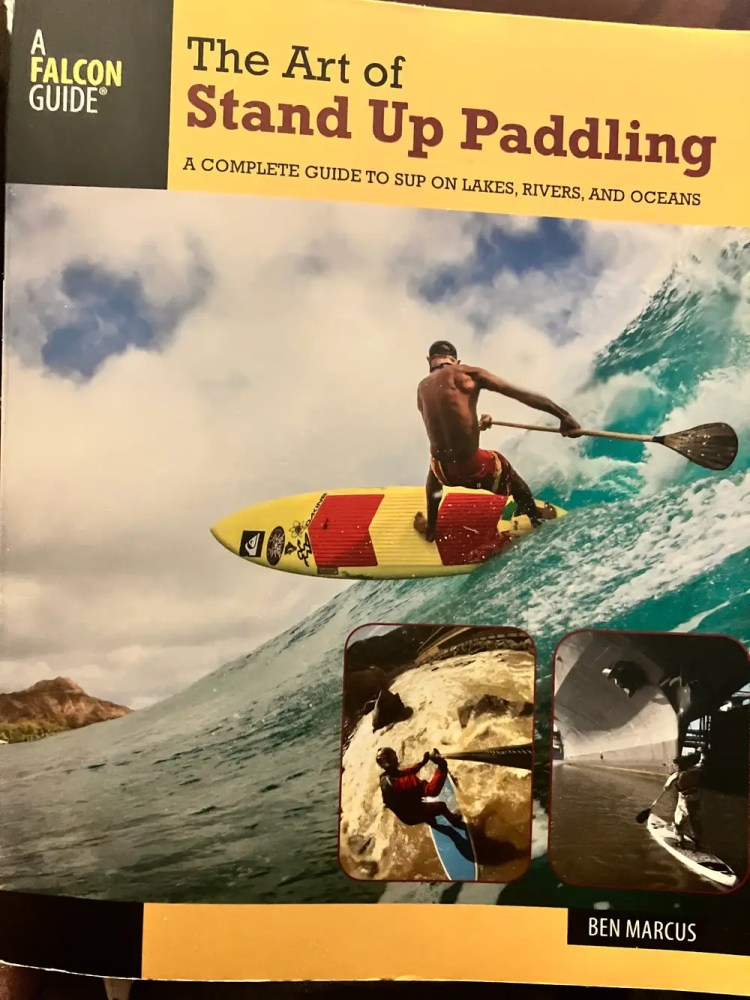 Book cover of 'The Art of Stand Up Paddling' featuring a surfer on a wave.